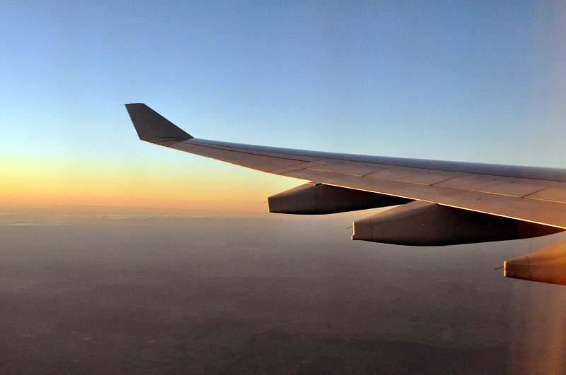 Airplane wing over sunset