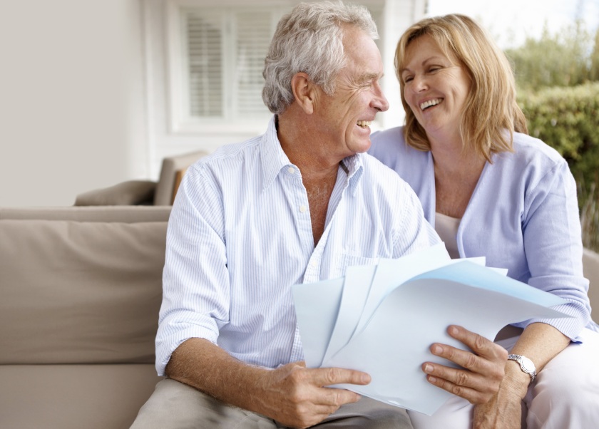 Elderly couple laughing with paperwork